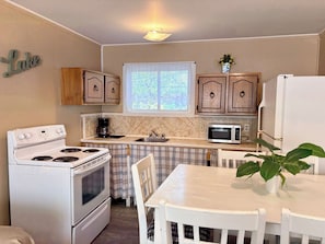 Une cuisine de taille réduite, équipée d’une cuisinière, d’un four à micro-ondes et de meubles de rangement en bois.