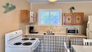 Cocina compacta con estufa, microondas y armarios de madera.