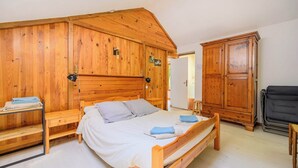 A wooden bedroom with a bed, a wooden wardrobe, and a bench.