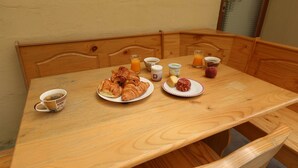 A wooden dining table with breakfast items including croissants, juice, and yogurt.