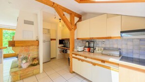 A kitchen with wooden beams, white cabinets, and a tiled backsplash.