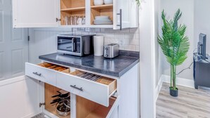 A modern kitchen with white cabinetry, a microwave, toaster, and a plant. - Charming 1BR Retreat Near DePauw University & Downtown Greencastle! (Greencastle)