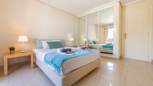 A modern bedroom with a large bed, bedside tables, a mirror, and a wardrobe. - Apartment Santa Monica (Albufeira)