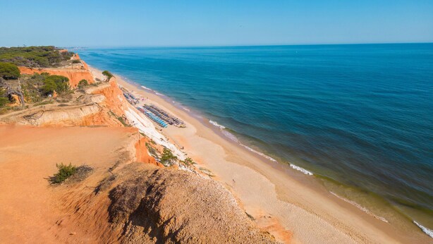 A coastal beach with a clear sky, sandy shore, and a cliff with vegetation. - Apartment Santa Monica (Albufeira)