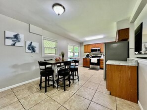 Une cuisine moderne avec un coin repas, comprenant un îlot central, des meubles en bois et un four à micro-ondes encastré.