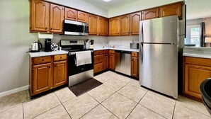 A kitchen with wooden cabinets, stainless steel appliances, and a tiled floor. - Cute Ranch home Middletown, OH (Middletown)