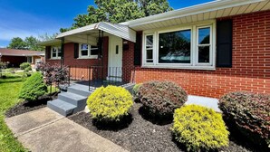 A two-story brick house with a front porch, a garage, and a well-maintained lawn with shrubs. - Cute Ranch home Middletown, OH (Middletown)