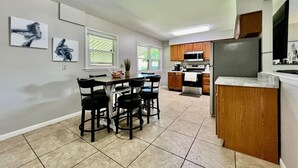 A modern kitchen with a dining area, featuring a central island, wooden cabinets, and a built-in microwave. - Cute Ranch home Middletown, OH (Middletown)