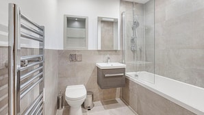 Un baño moderno con cabina de ducha de vidrio, inodoro blanco y tocador con lavamanos.