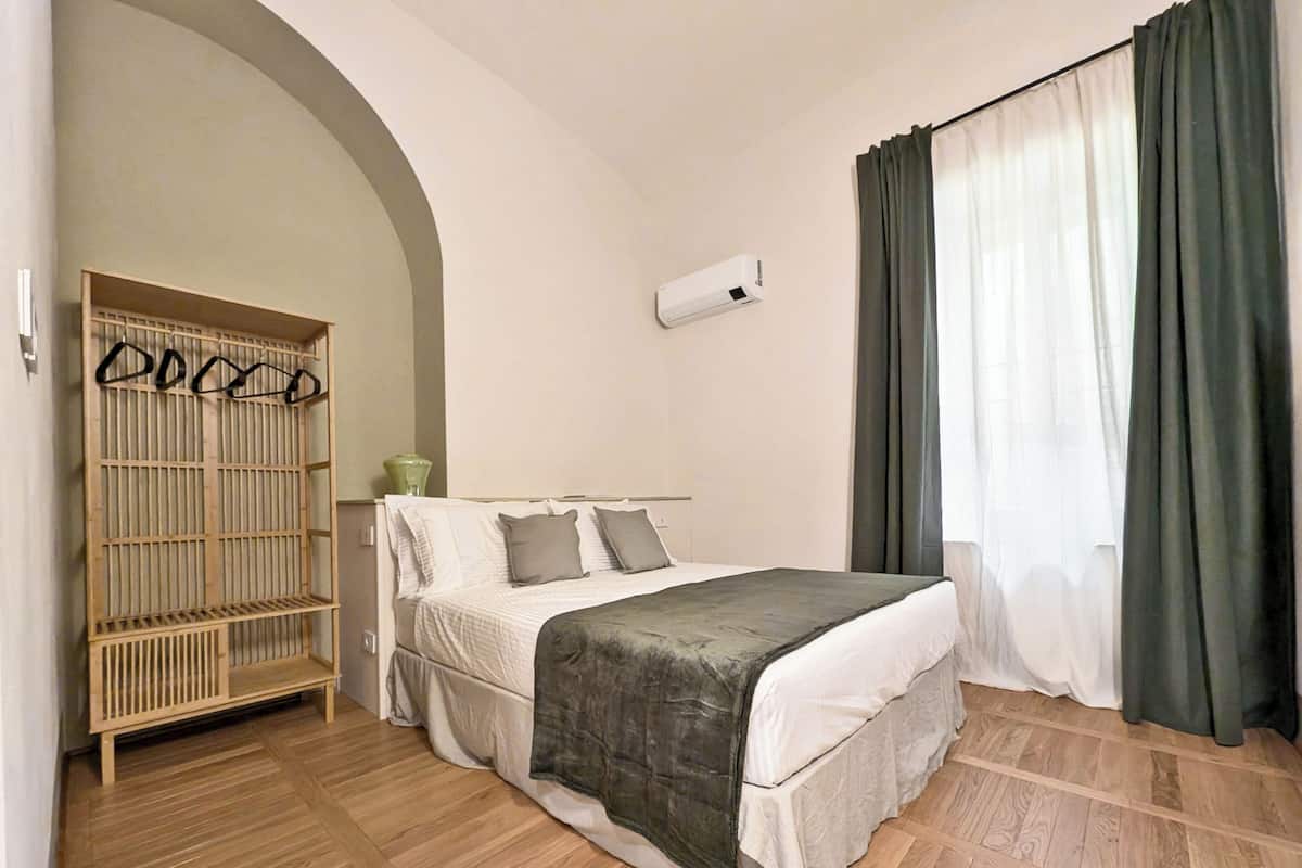 Ein Schlafzimmer mit Bett, Kleiderschrank und einem Fenster mit Vorhängen.