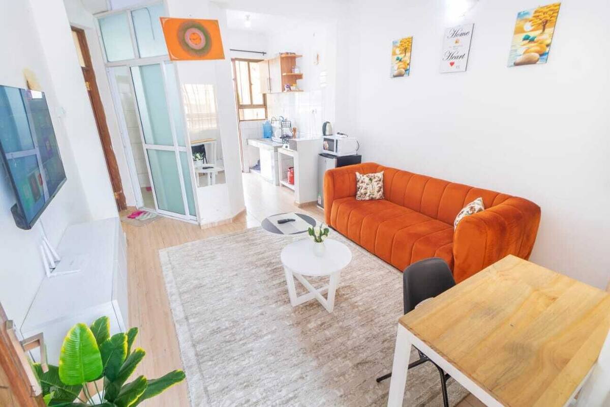 Una sala de estar moderna con sofá, una mesa de comedor y una zona de cocina al fondo.