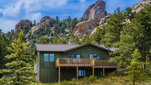 Eine Hütte mit Balkon, umgeben von Bäumen und Bergen.
