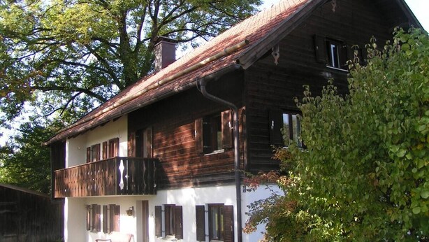 A two-story wooden house with a balcony, a small porch, and a garden area. - Landhaus - Nahe Starnberger See (Eberfing)