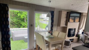 A modern kitchen with a dining area, a TV, and a view of the outdoors. - Luxury Rural Hottub Lodge in Northumberland (Morpeth)