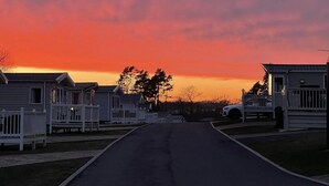 A row of mobile homes with a road in front, set against a sunset sky. - Luxury Rural Hottub Lodge in Northumberland (Morpeth)