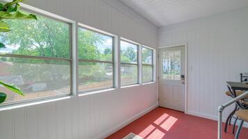 A room with large windows, a door, and a table with chairs.