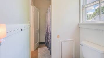 A narrow hallway with a white radiator, a door, and a window with a view of trees and a house.