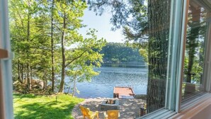 A lakeside view from a window with a deck area featuring outdoor seating and a fire pit. - Lakeside Guest House - Porters Lake (Porters Lake)