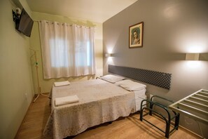 A bedroom with a bed, a headboard, a window with curtains, a wall-mounted picture, and a bedside table. - Pousada Rio Uruguai (Uruguaiana)
