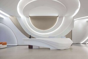 A modern reception desk with a curved design, surrounded by smooth, curved walls and a minimalist aesthetic. - Days Inn by Wyndham Pingxiang Wugong Mountain (Pingxiang)
