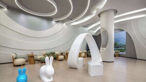 Un interior moderno con muebles blancos únicos, incluyendo un gran arco blanco y una escultura de conejo azul.
