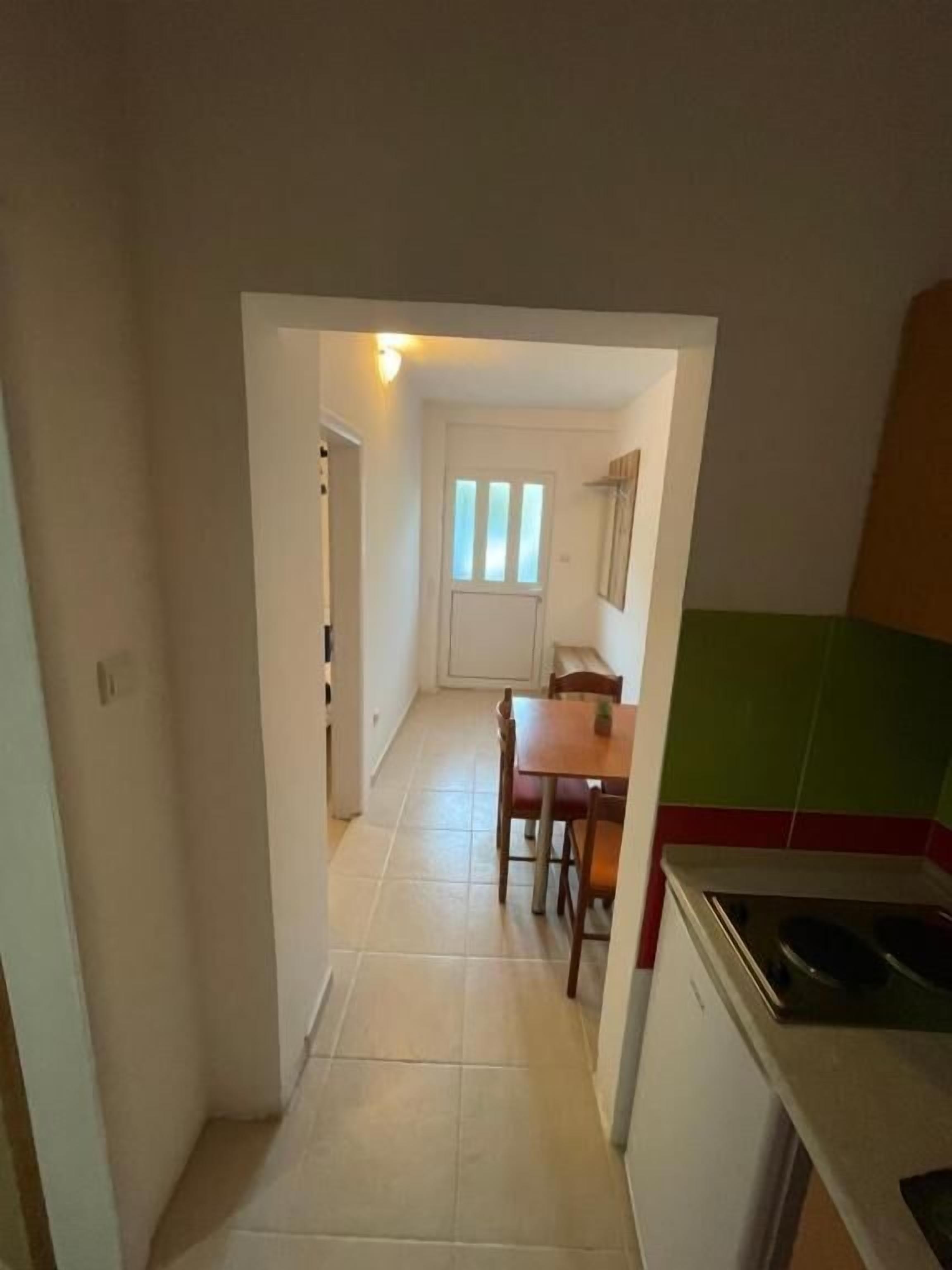 A narrow hallway leading to a dining area with a table and chairs.