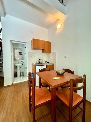 Una cocina funcional con armarios de madera, un lavamanos y una mesa de comedor con sillas.