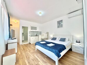 Una habitación de hotel moderna con una cama grande, un escritorio, una silla y una kitchenette.