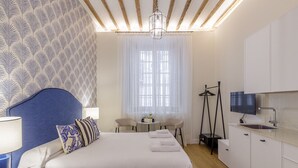 Een moderne hotelkamer met een groot bed, een bureau, een stoel, een televisie en een kitchenette.