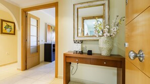 Un pasillo con una puerta de madera, una consola con un florero y un espejo encima.