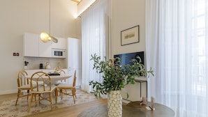 Een moderne keuken met witte kastjes, een magnetron en een eethoek met een ronde tafel en stoelen.