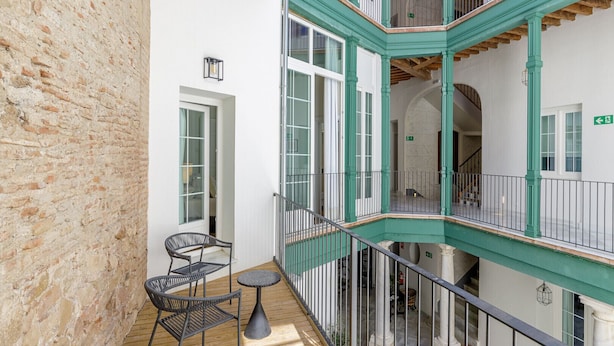 Een balkon met meerdere niveaus, houten vloer, zwarte rieten stoelen en een klein rond tafeltje.