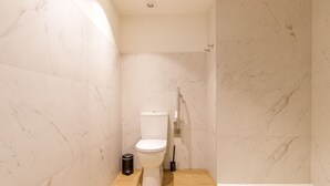 Een badkamer met toilet, bidet en douche.
