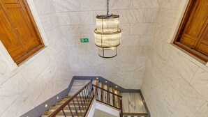 En trappa av marmor med träräcken och en hängande lampa.