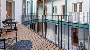 Une terrasse en bois à plusieurs niveaux, dotée d’un espace salon extérieur, d’un escalier et offrant une vue sur l’intérieur.