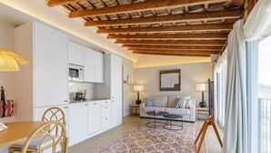 Una cocina moderna con armarios blancos, techo de madera y un comedor con mesa y sillas.
