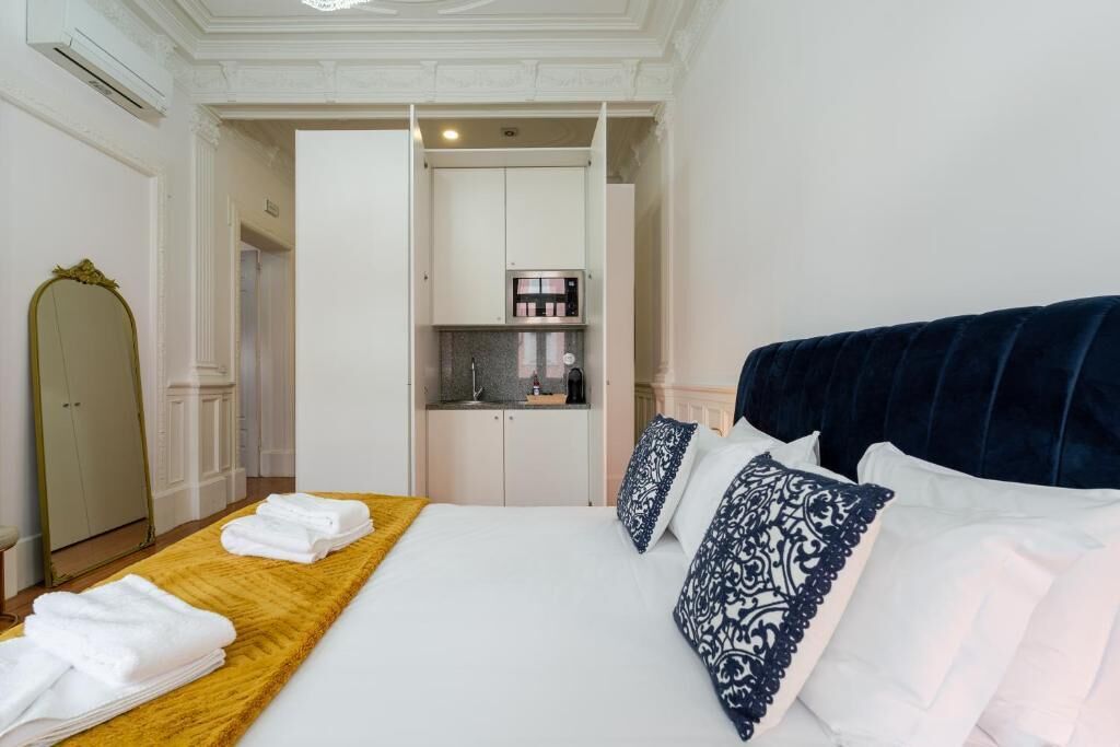 Ein Hotelzimmer mit Bett, Holzboden, Spiegel, integrierter Küche und Kleiderschrank.