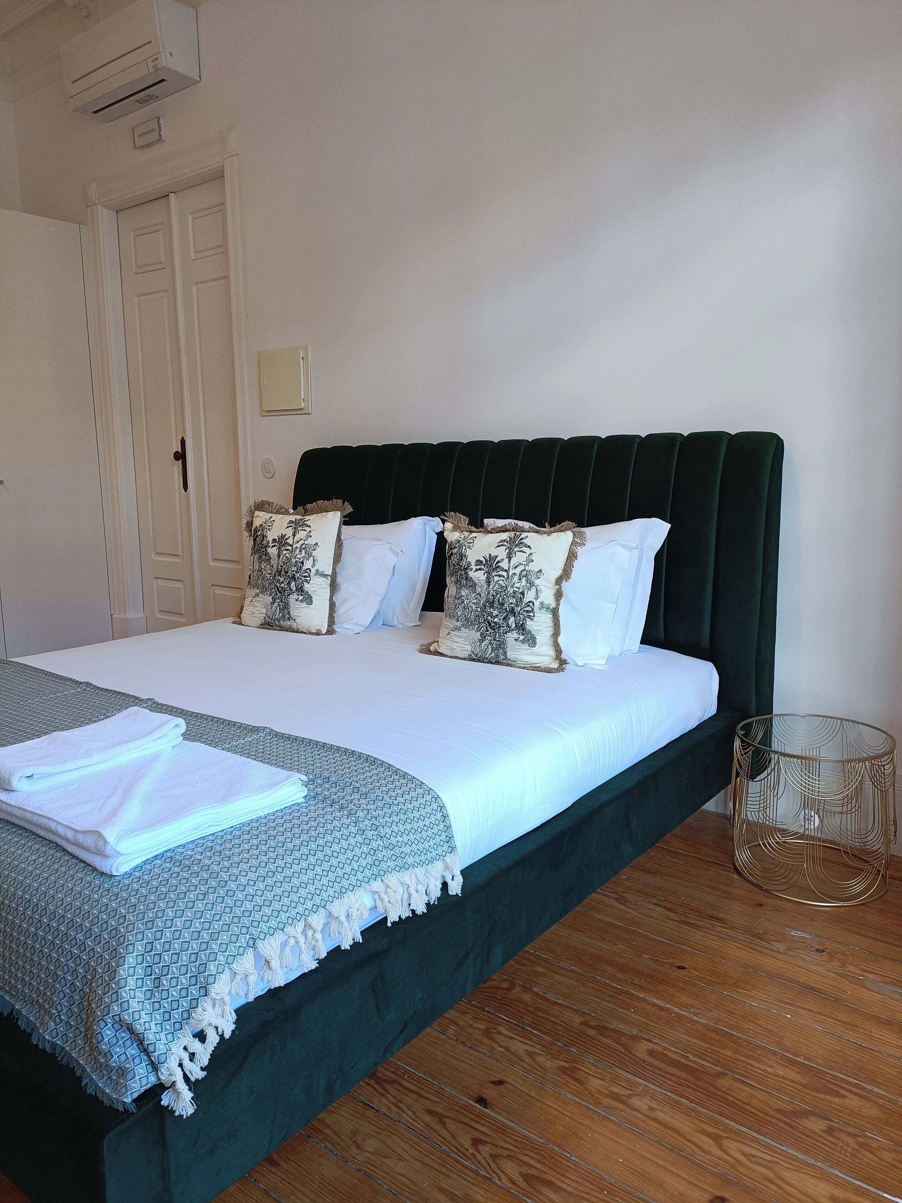 A neatly made bed with a dark headboard, white bedding, and patterned pillows.