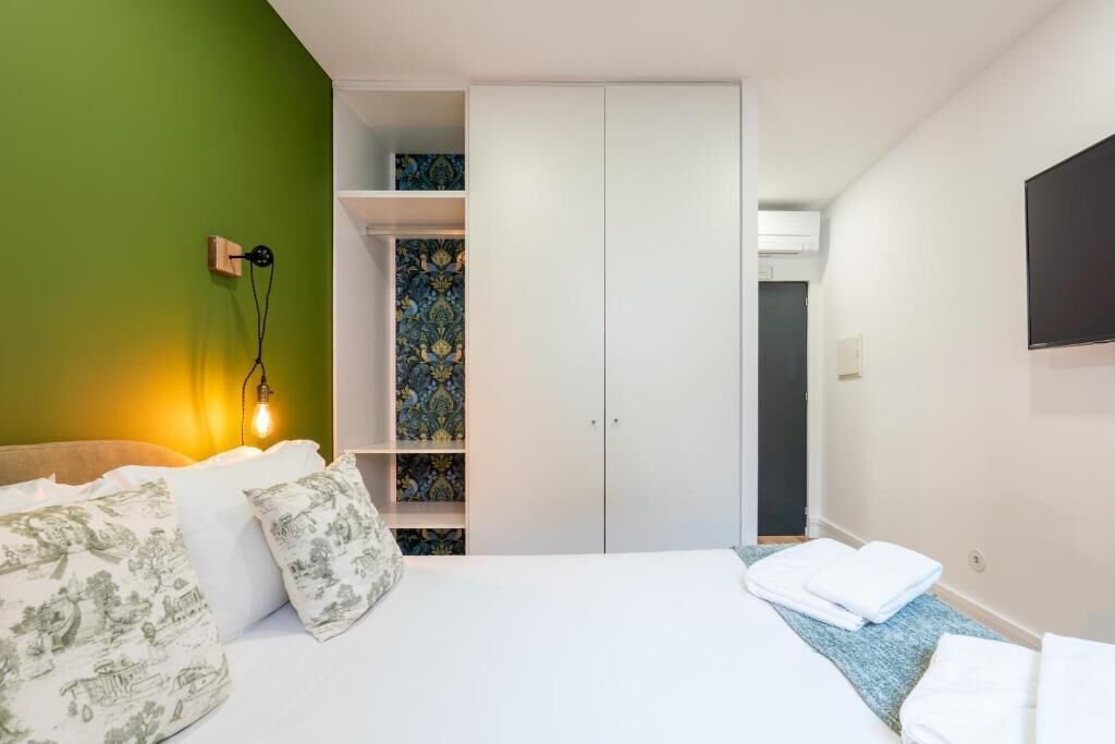 Un dormitorio con cama, armario y televisor montado en la pared.