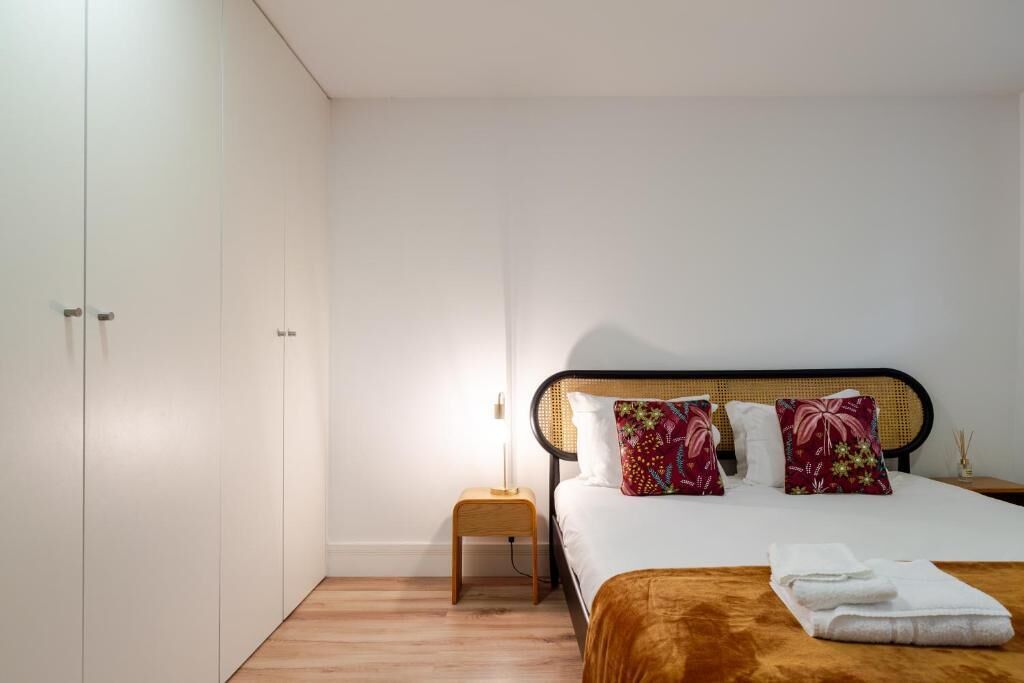 A bedroom with a bed, pillows, a nightstand, and a wardrobe.