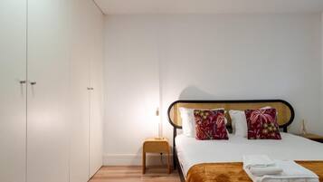 A bedroom with a bed, pillows, a nightstand, and a wardrobe.