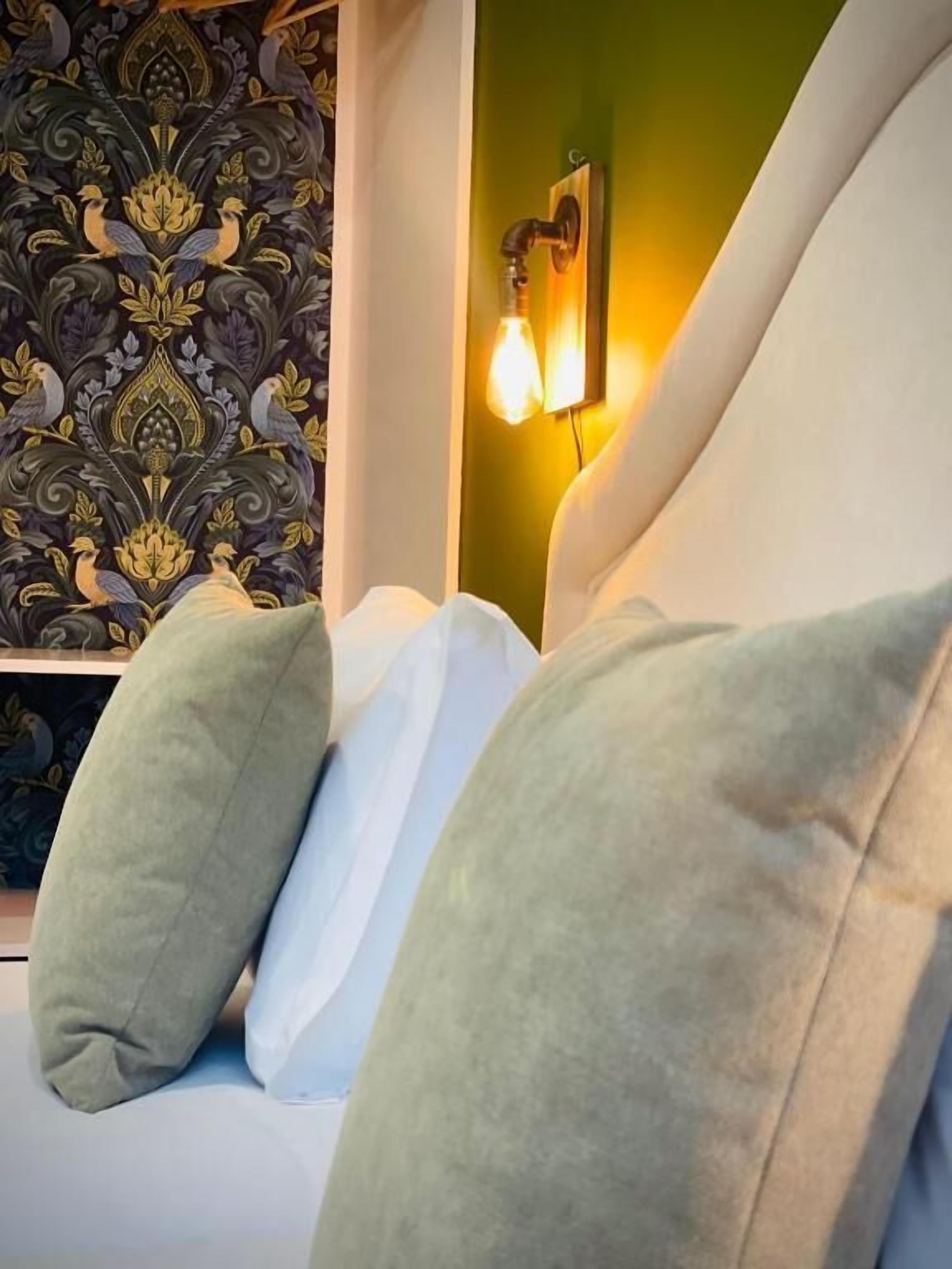 Una cama con almohadas verdes y una pared con un diseño decorativo.