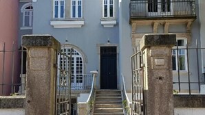 Un edificio con una entrada central, escalones de piedra y una reja negra.