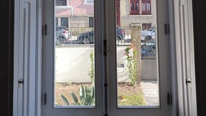 Una puerta blanca con un panel de vidrio, que muestra una vista de la calle con coches aparcados y edificios.