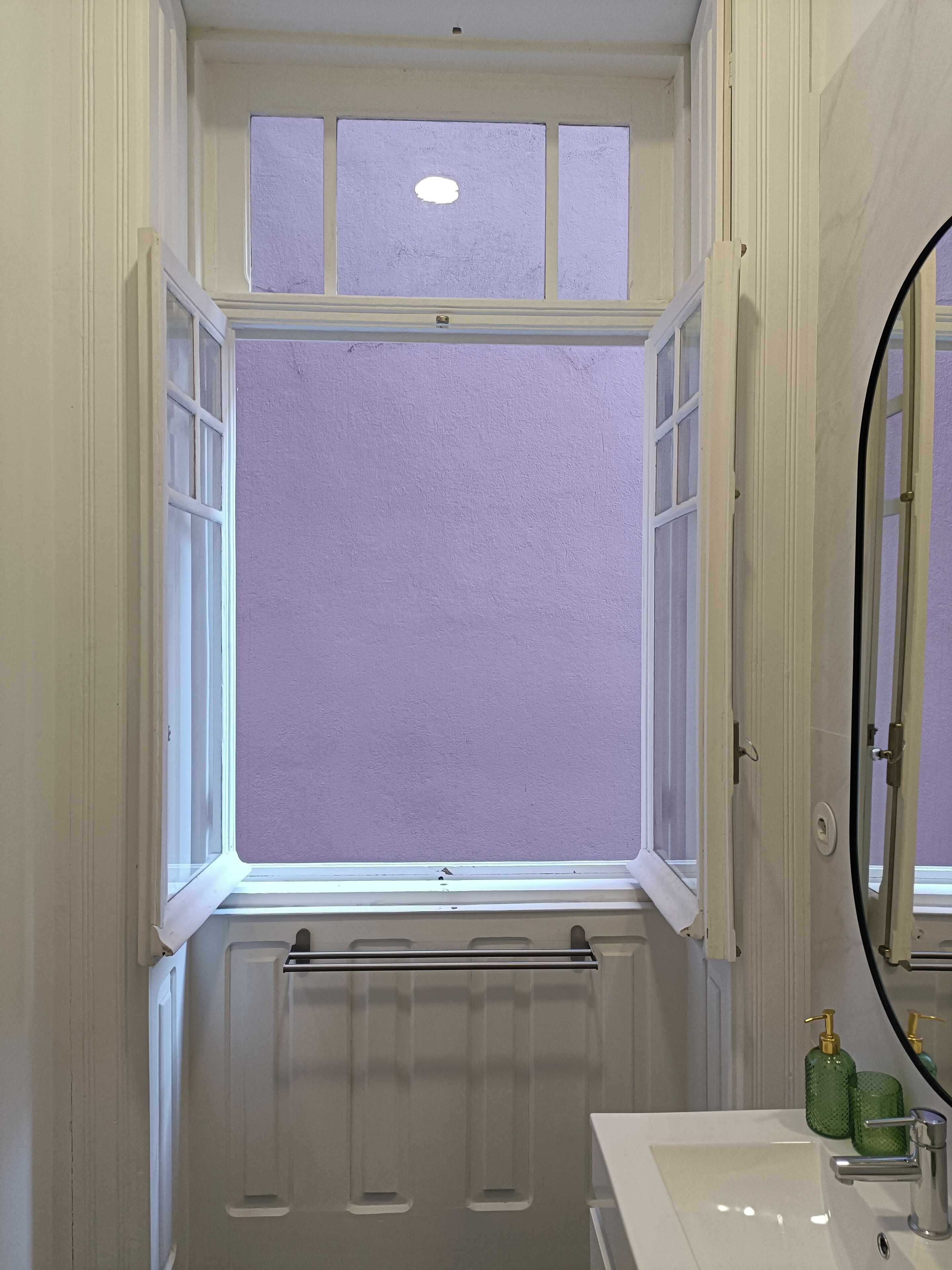 A bathroom with a window, a sink, and a mirror.