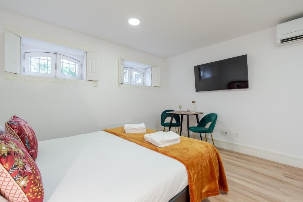 Ein Hotelzimmer mit einem Bett, zwei Stühlen, einem kleinen Tisch und einem Fernseher an der Wand.