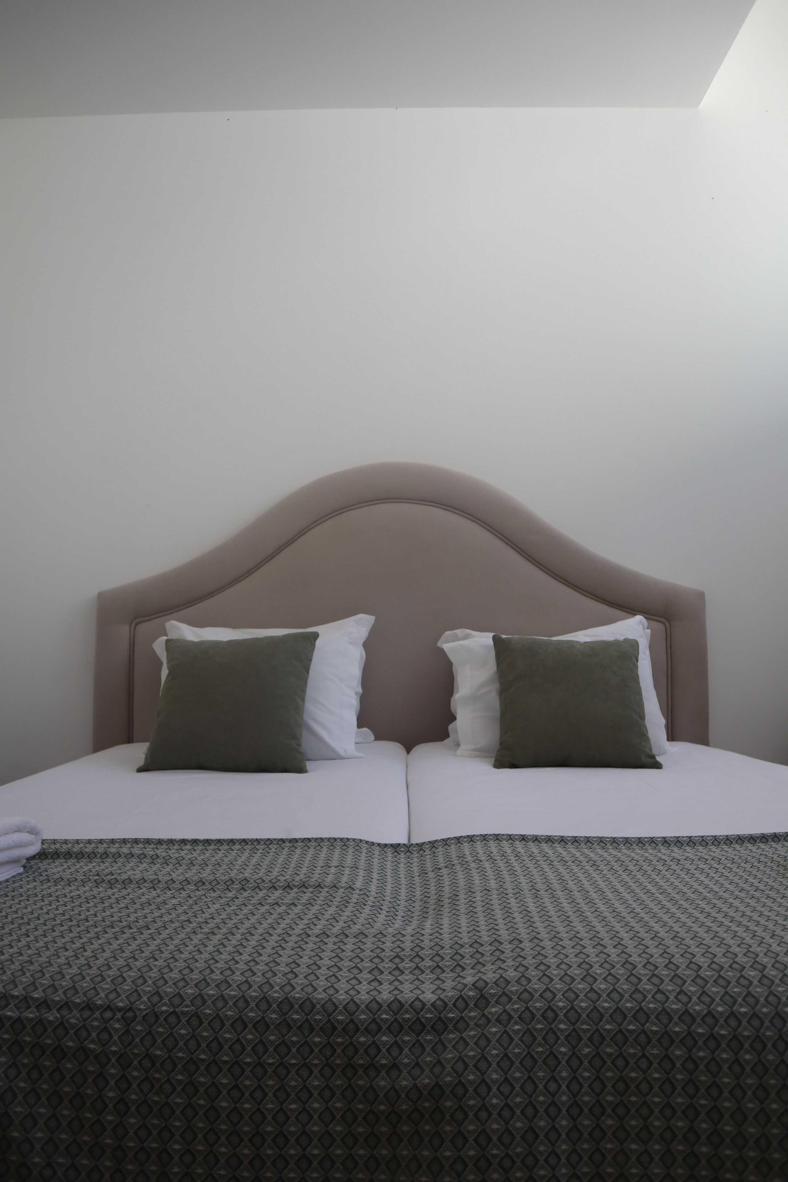 A bed with a headboard, two pillows, and a patterned bedspread.