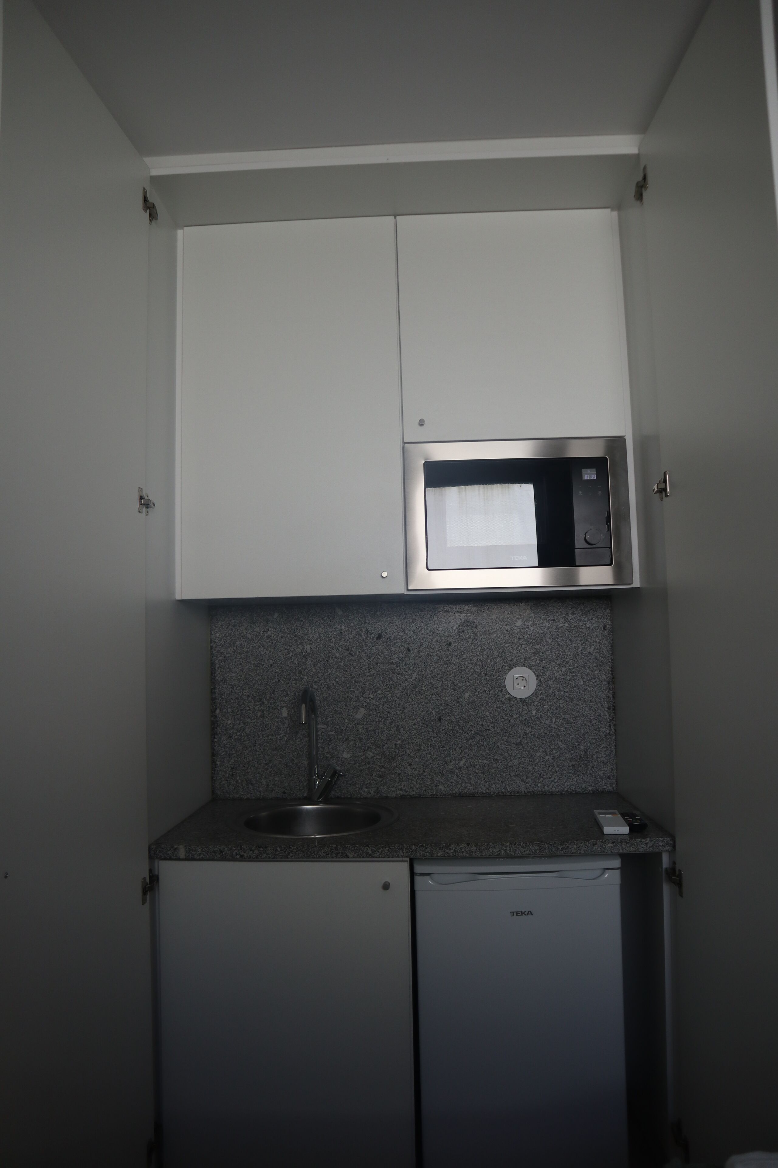 A compact kitchenette with a built-in microwave, a sink, and a small refrigerator.