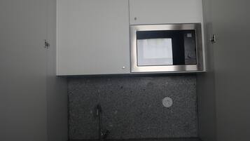A compact kitchenette with a built-in microwave, a sink, and a small refrigerator.