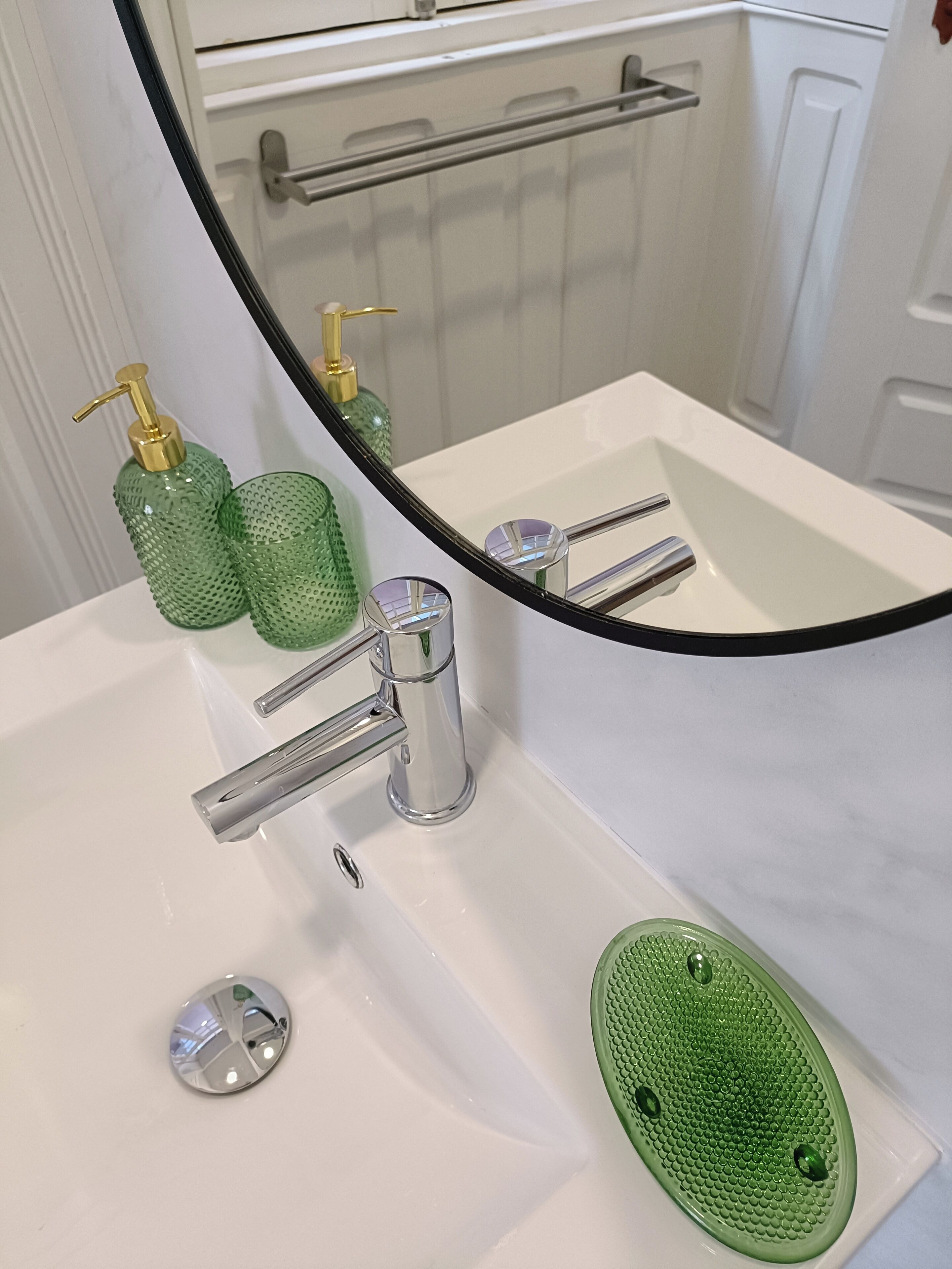 A bathroom with a white sink, chrome faucet, and green textured soap dispenser.